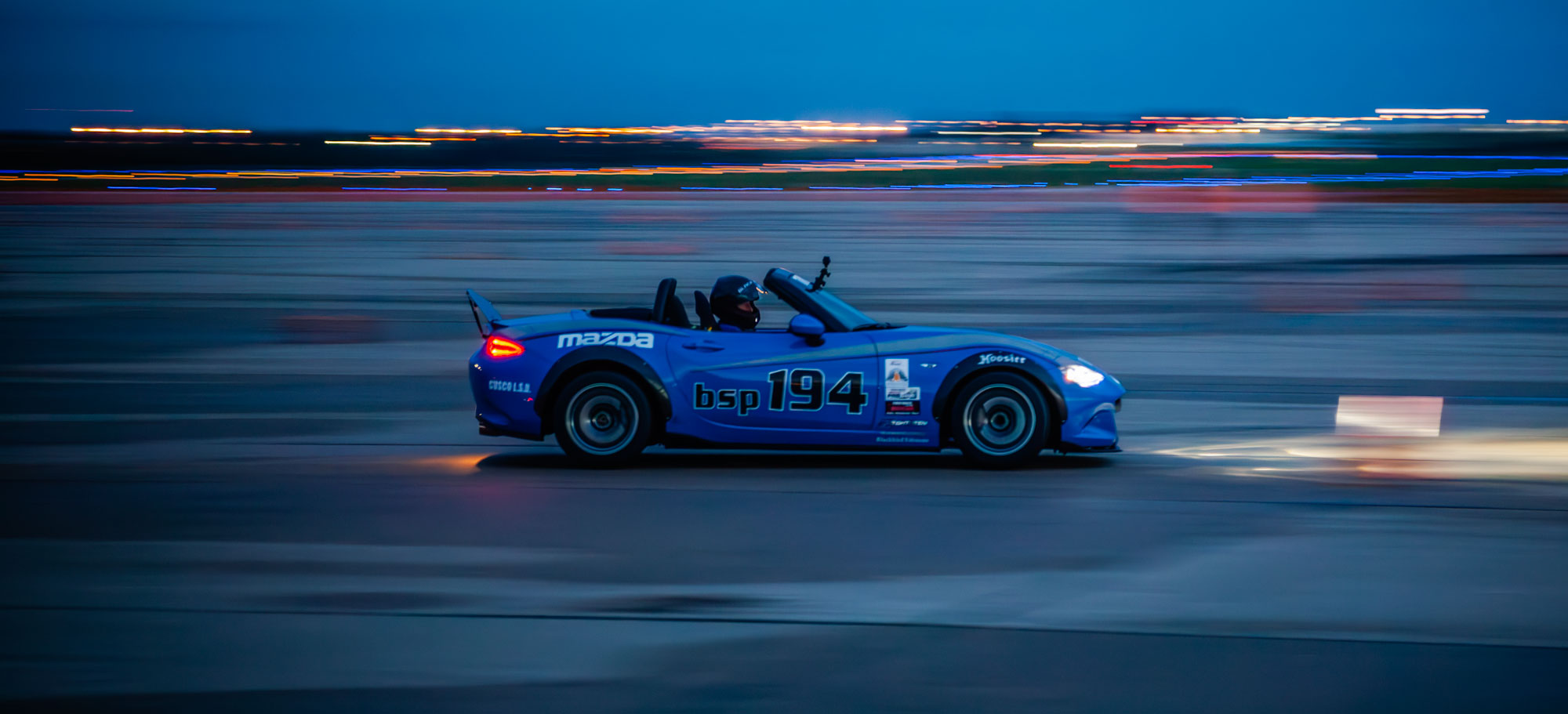 A blue Mazda Miata autocrossing in the dark at the 2018 Solo National Championships A blue Mazda Miata autocrossing in the dark at the 2018 Solo National Championships